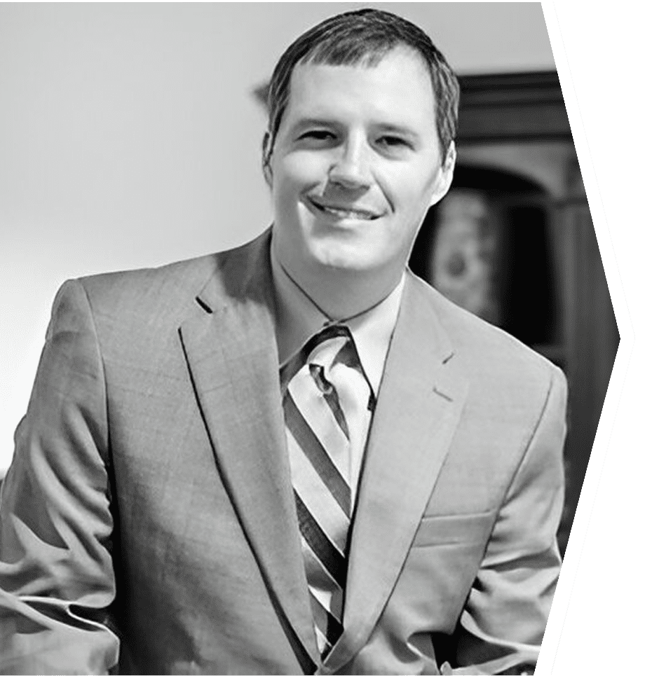 Man in suit smiling in black-and-white photo.